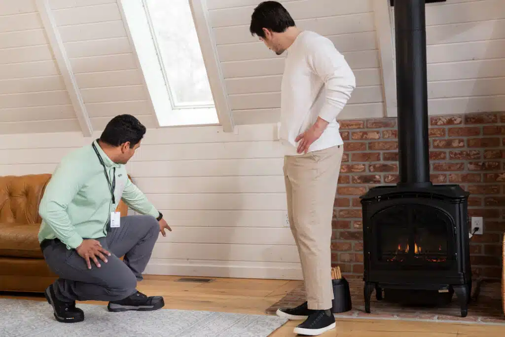 Aptive Pest Control Specialist Inspecting A Floor Vent With A Homeowner In A Cozy Attic Space.