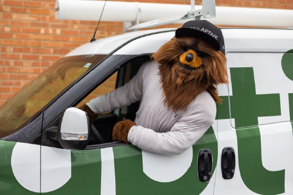 Jazz Bear, The Utah Jazz Mascot, Wearing An Aptive Cap, Leans Out Of The Driver'S Window Of An Aptive Van.